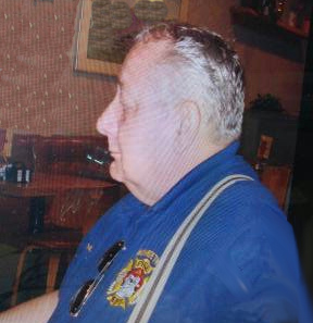 William in profile, wearing a blue fireman polo shirt with suspenders. 
